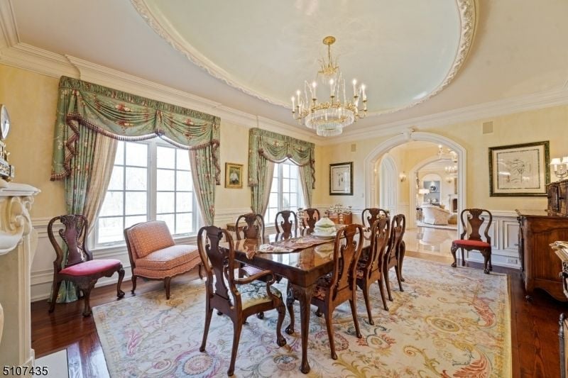 The dining room features wooden furniture, and the chandeliers give the room a luxurious feel.