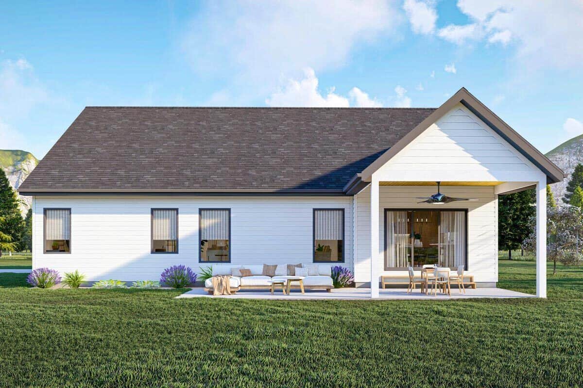 The gabled porch extends to a concrete patio furnished with a cushioned sectional and round tables.