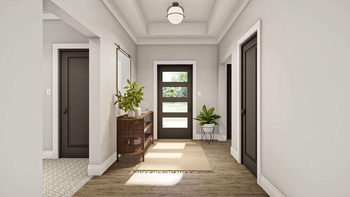 Foyer with a tray ceiling, a tasseled rug, and a wooden console table topped with a brass framed mirror.