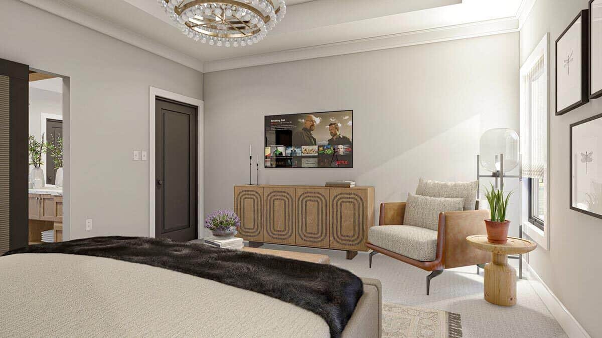 The primary bedroom includes a cushioned armchair and a TV mounted above the wooden dresser.