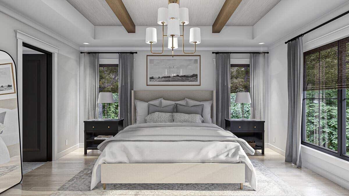 The primary bedroom features a gray wingback bed and a tray ceiling adorned with exposed wood beams and a brass chandelier.