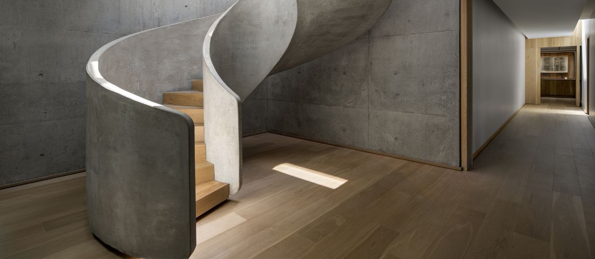 The spiral stairs are made of concrete and light wood.
