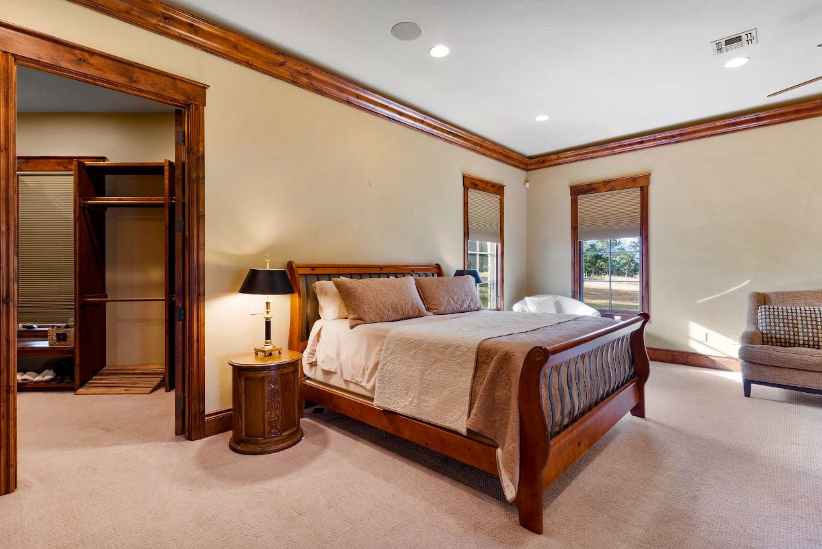 The bedroom features wall-to-wall carpeting, and the wooden bed gives the room a rustic and cozy feel.