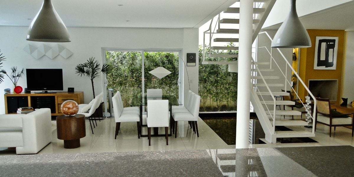 The dining area is in between the living room and the floating staircase.