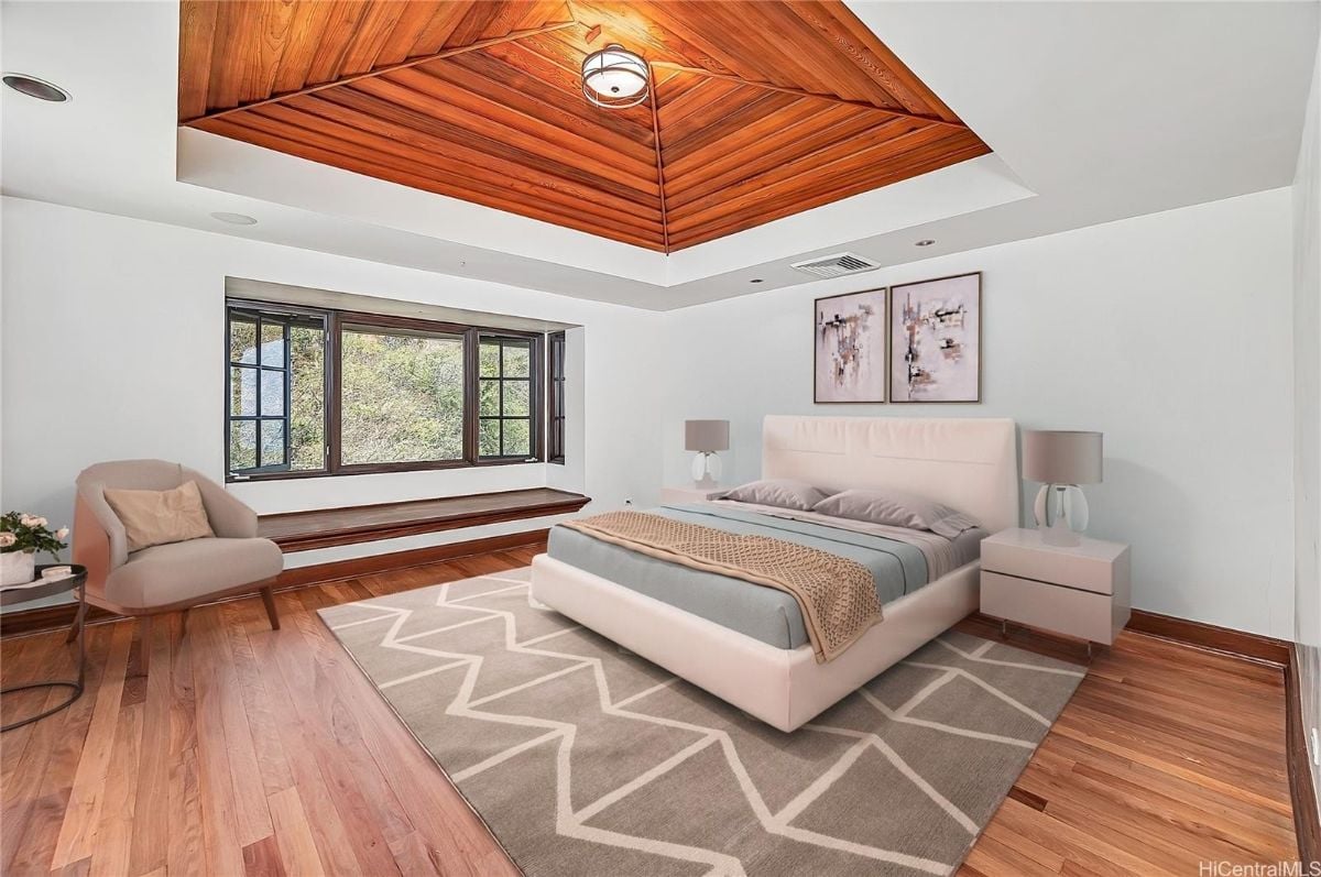 The bedroom features a queen-size bed and a windows seat, giving off a cozy feel to the room.