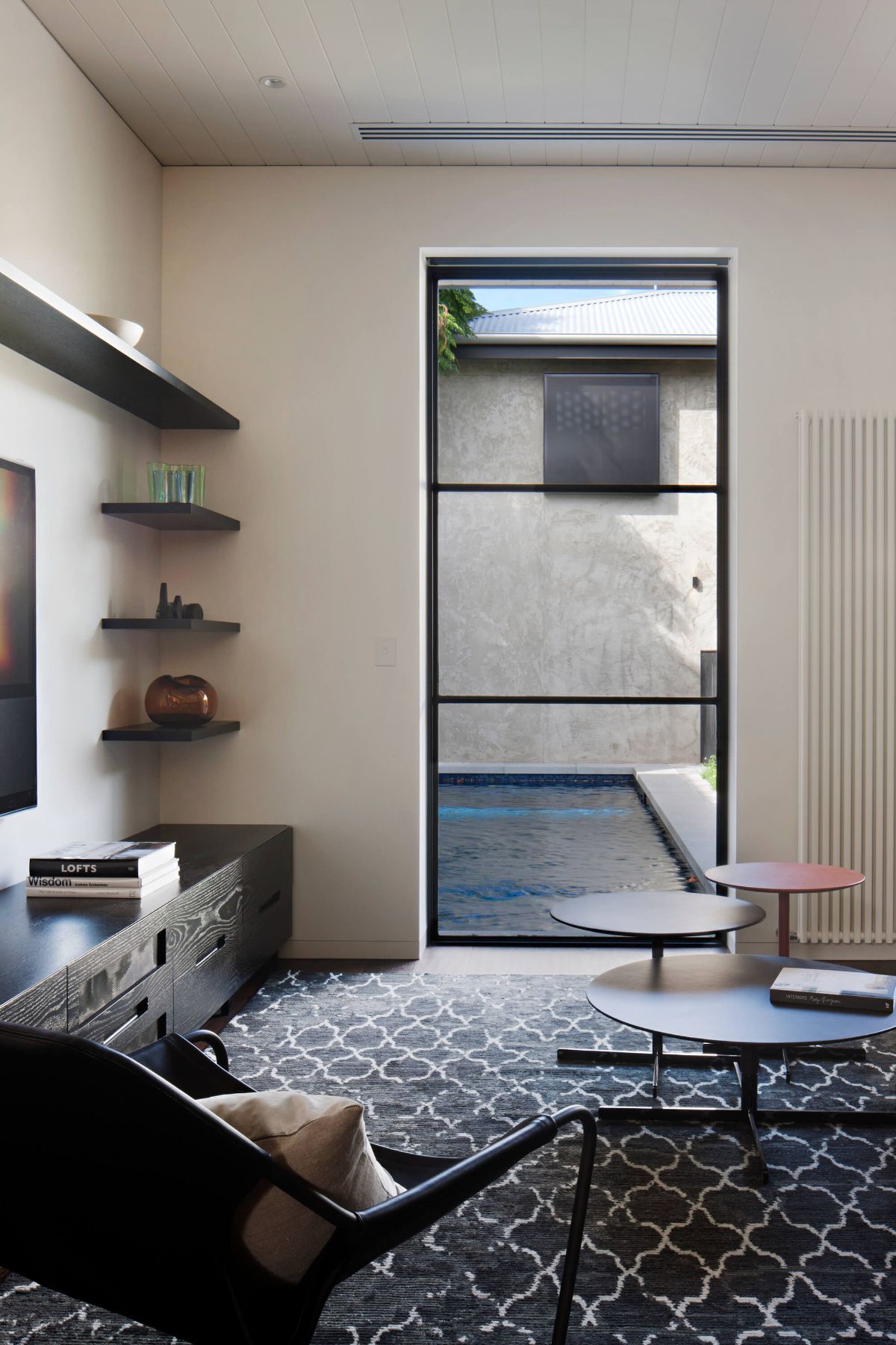 The study features a unique coffee table and large glass walls overlooking the edge of the pool.