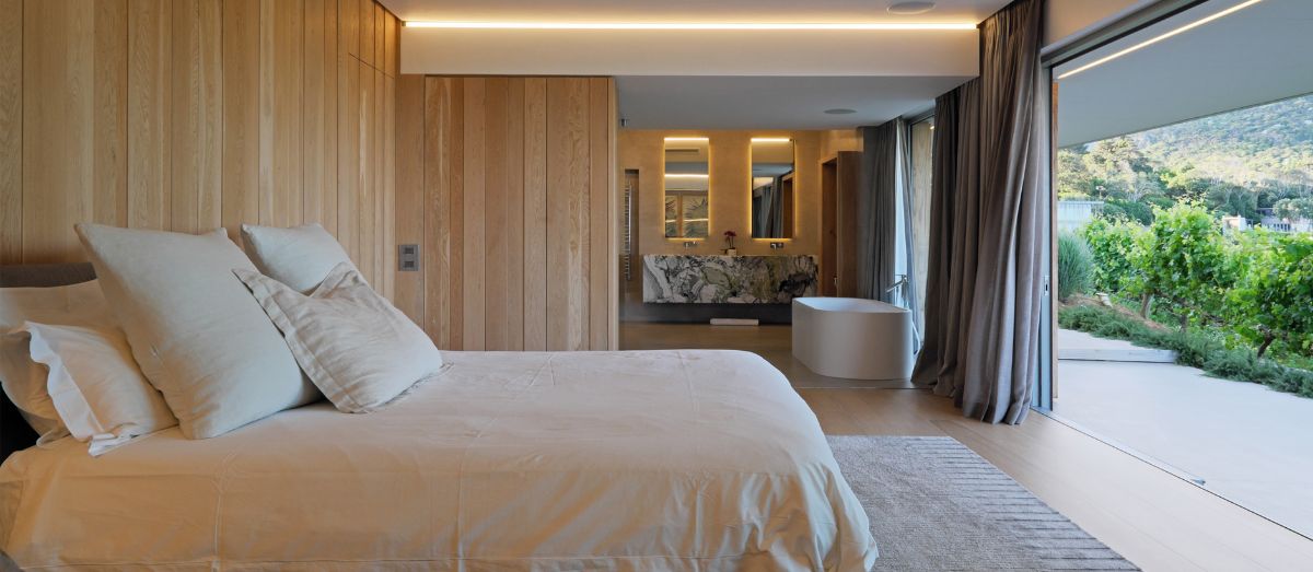 The master bedroom, with a large sliding glass door that provides a panoramic view of the surrounding mountains.