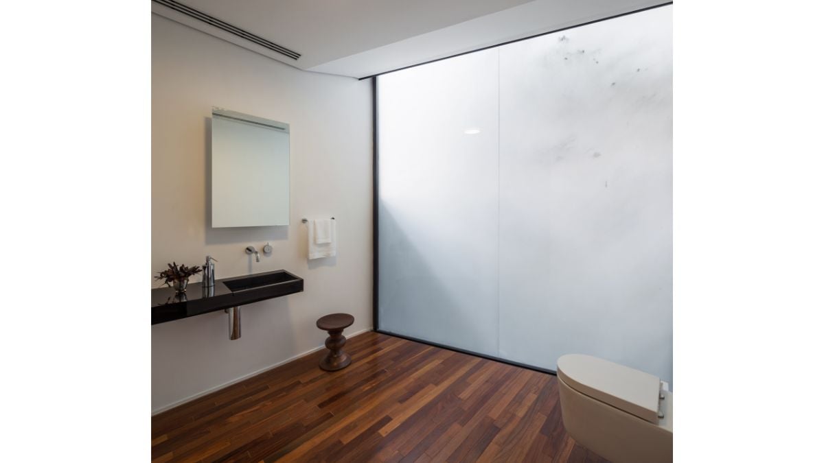 White ceiling and walls, a wooden floor, and a simple yet attractive design characterize the bathroom's spaciousness.
