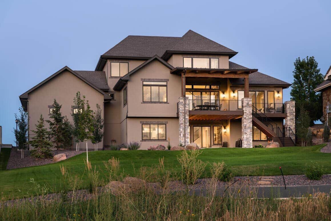 Rear exterior view with a multitude of windows along with a covered patio and decks complemented with an exterior staircase.
