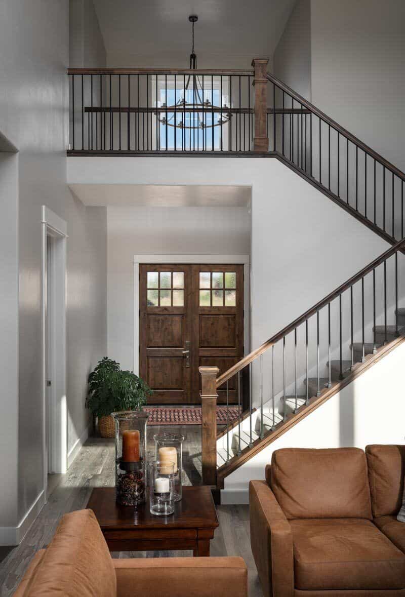 The foyer has double front doors, a wooden staircase, and a view of the living room ahead.