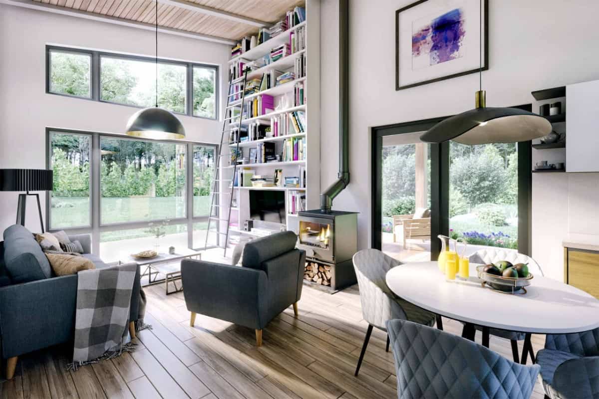 The living room has gray modern seats, a wood stove, built-in shelves, and huge windows that look out the rear deck.