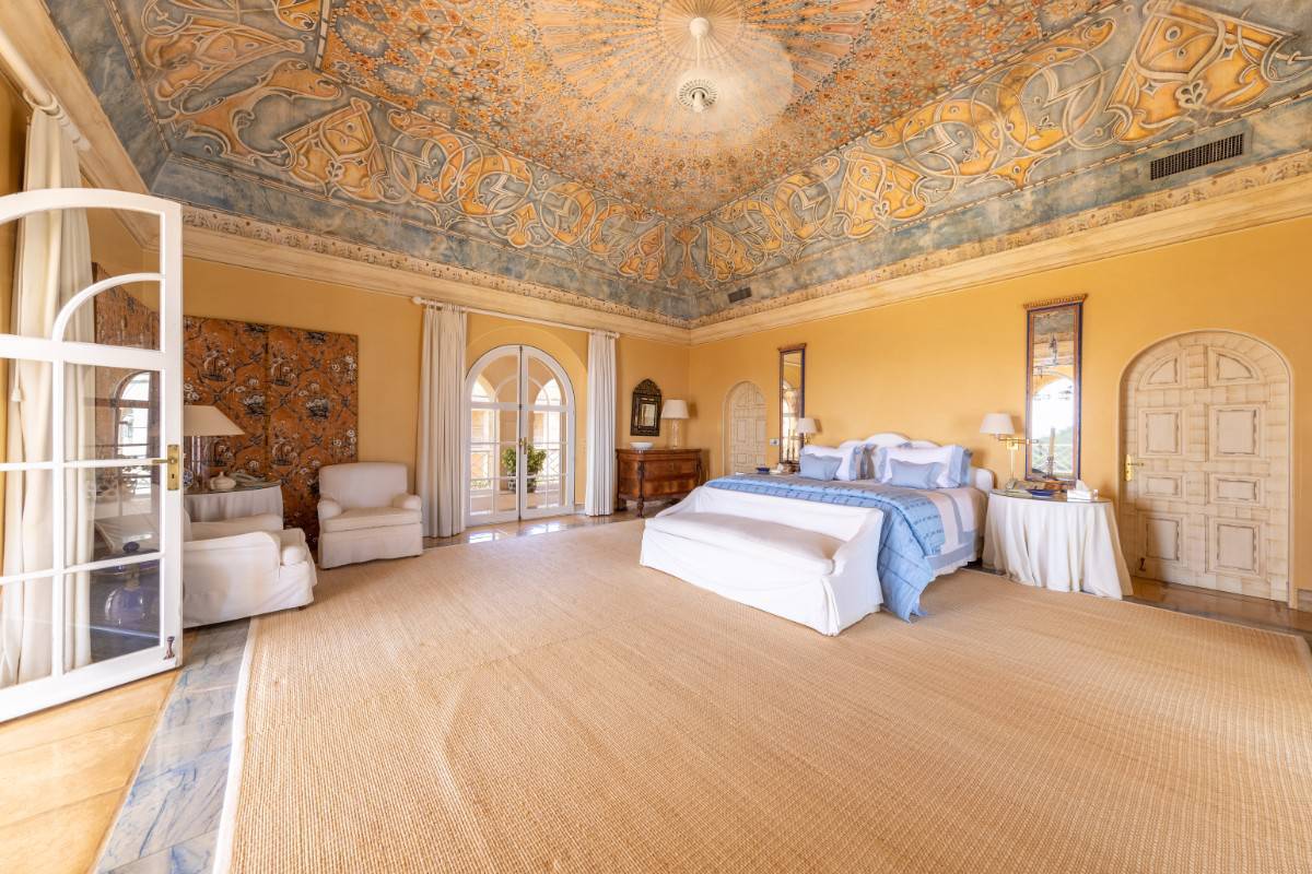 A coved ceiling graced with hand-painted mural crowns this bedroom.