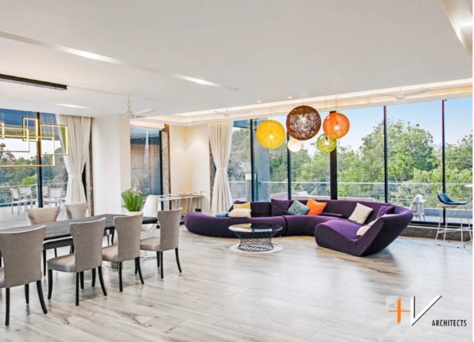 This spacious kitchen and living area, filled with a violet S-shaped sofa, also offers a nice view outside.