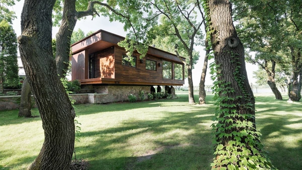 A distant exterior shot capturing a chalet nestled amidst lush green surroundings.