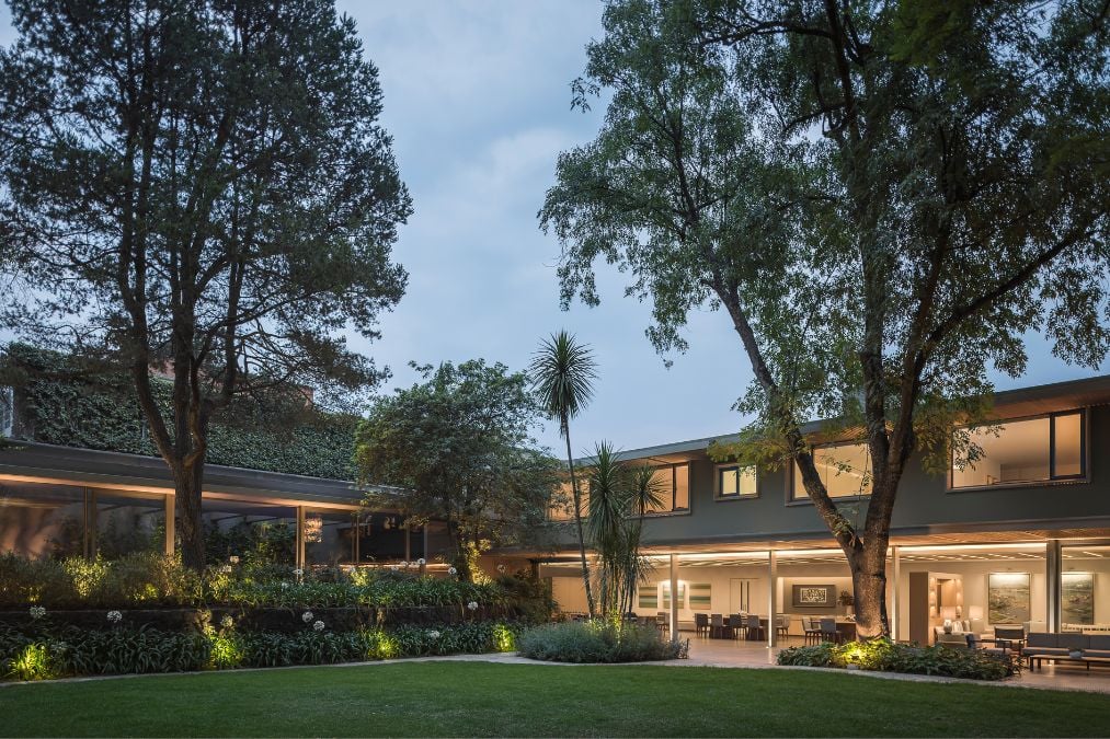 The house's exterior has been photographed at nighttime, showcasing its intricate openwork structure as well as the spacious lawn and garden area, creating a stunning visual display.