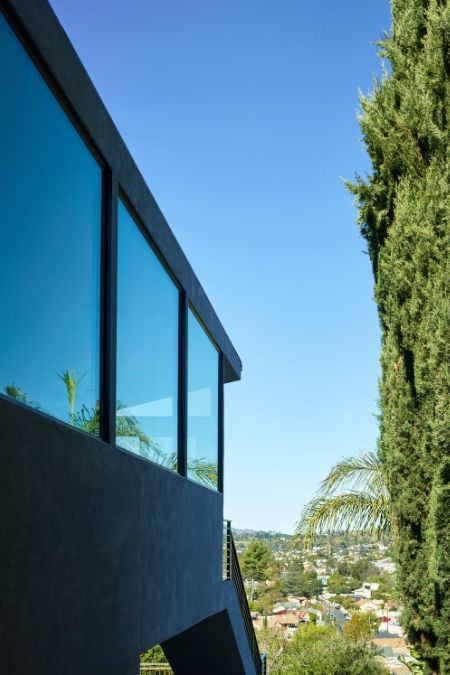 This photograph captures a view of a cityscape as seen through a window situated on the upper level of a house.