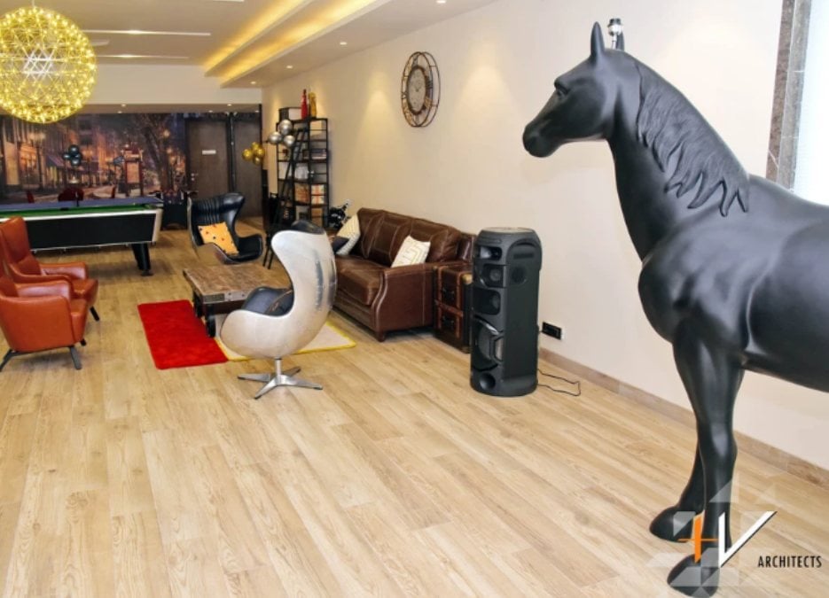 An interior shot of a gaming room filled with a small billiard table and a black horse sculpture.