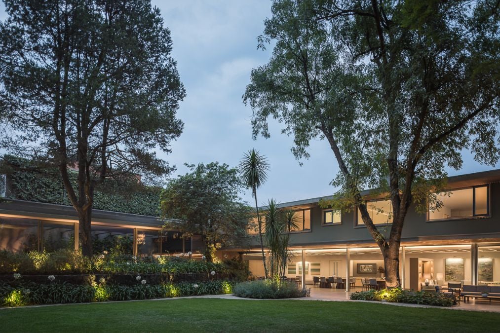 An elegantly designed house with a landscaped lawn and carefully placed trees that enhance its visual appeal.