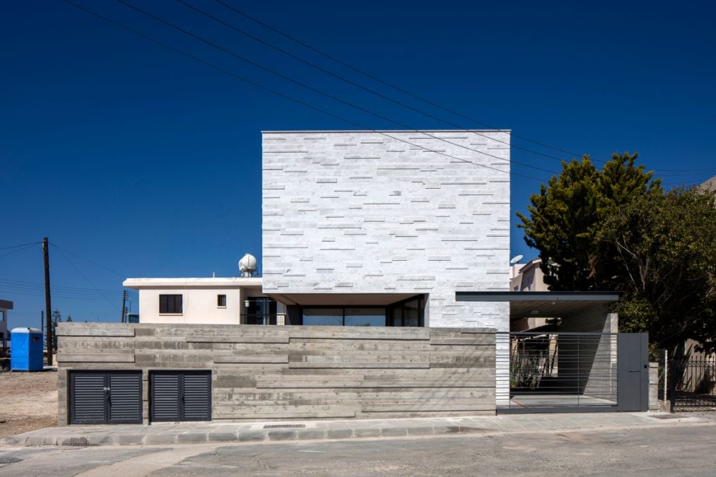 This exterior shot of the Portidis house showcases the marble-clad house and a beautiful facade fence.