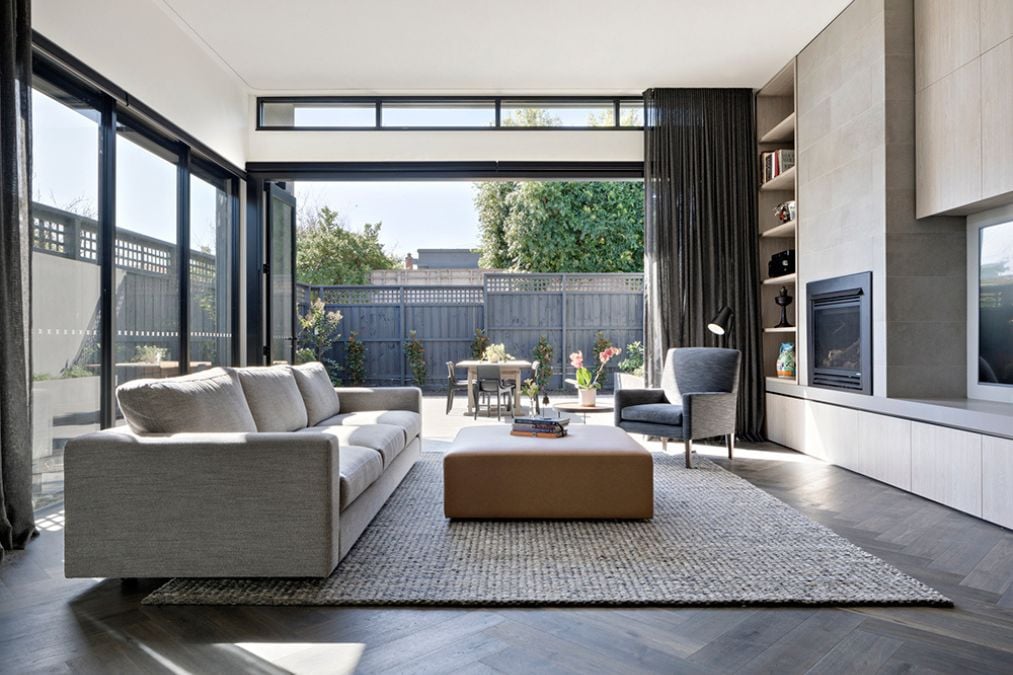 The spacious high-ceiling interior is adorned with modern furniture and features massive glass walls that let in ample natural light, creating an inviting and visually stunning space.