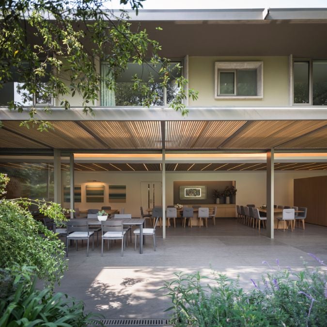 The photo showcases a patio area with multiple dining sets arranged under a roof.