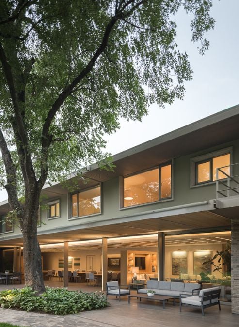 This close-up shot showcases a grand and spacious house, featuring a generously-sized first floor and a magnificent tree standing proudly in front of it. 