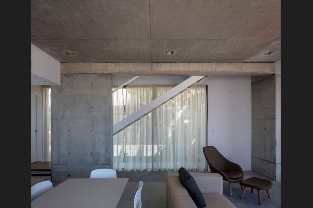 This interior shot showcases the living room area with a raw concrete layout that stands out in the design.