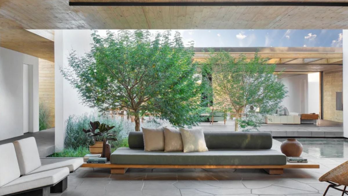 A different view of the outside living space with a landscape and a portion of the pool.