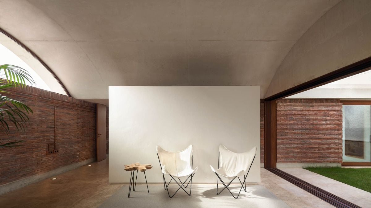 This interior shot showcases a spacious area with a white backdrop and two butterfly chairs, creating a serene and minimalist ambiance that is both inviting and modern.