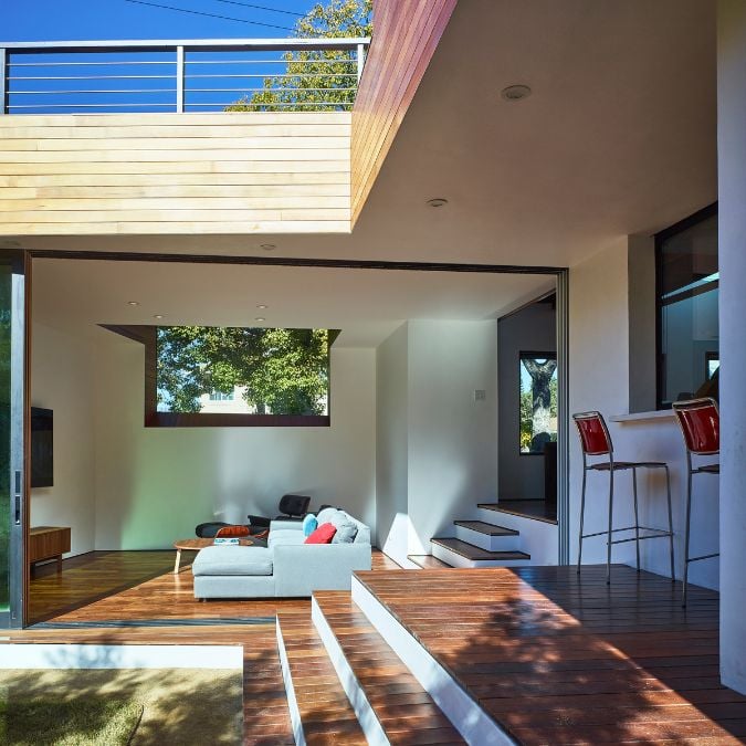 An exterior shot which portrays a living room and a glimpse of the roof deck railing, as seen from an external viewpoint.