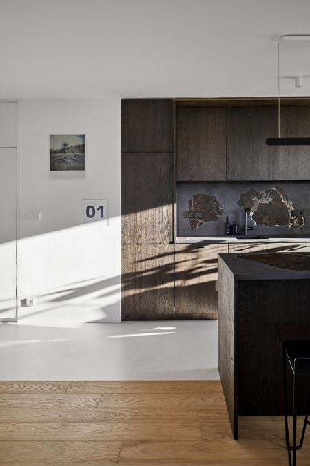 This is a partial view of the kitchen section where the wooden plank floors end, and the flooring transitions to a pure white color, extending to the edge of the space.