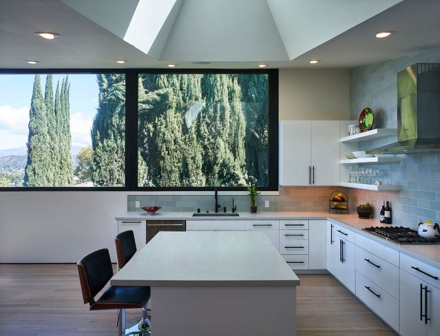 This photograph captures the interior of the kitchen area, which features a sizable window and the white countertop adds a touch of elegance and modernity to the overall design.