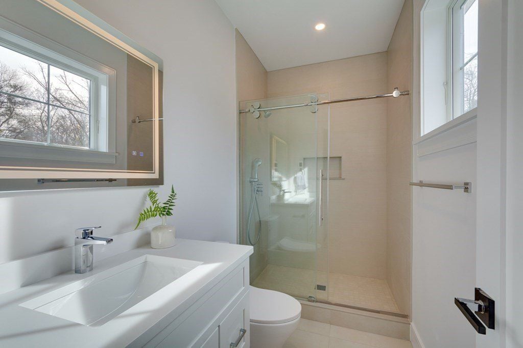 The bathroom features a vanity with a tile countertop and a shower with a glass enclosure.