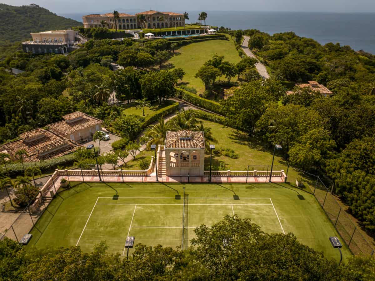 The estate includes a tennis court surrounded by lights.
