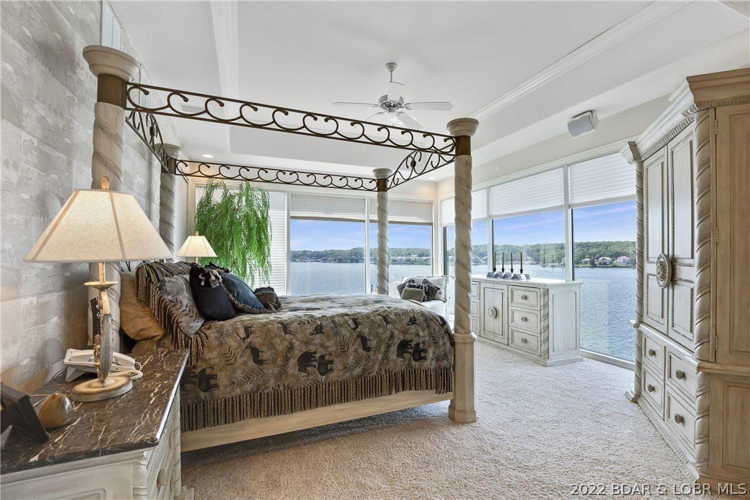 The bedroom features a wall-to-wall carpet, a wooden cabinet, and a luxurious canopy bed that gives off a cozy feel.