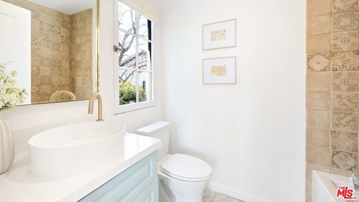 The bathroom features a vanity with a vessel sink and an elegantly framed mirror.