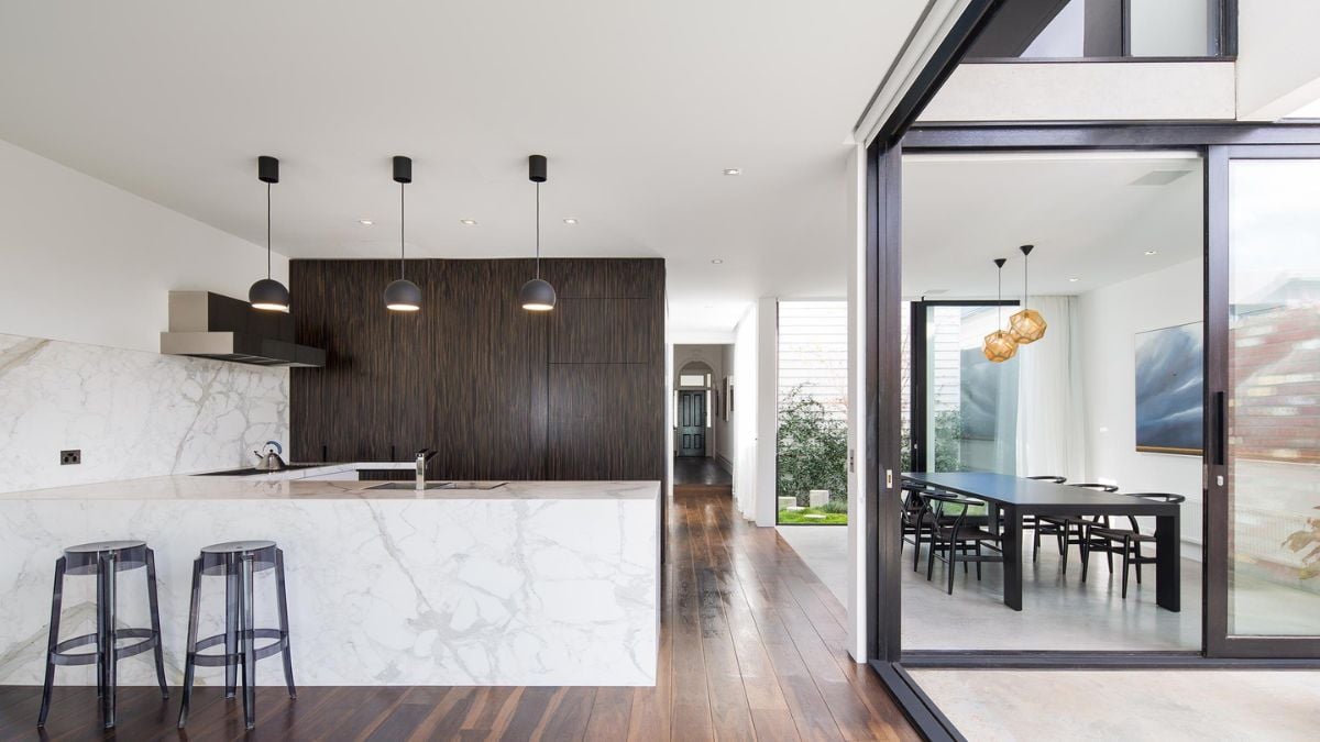 An interior shot showcasing a kitchen with a marble countertop located adjacent to a dining room table.