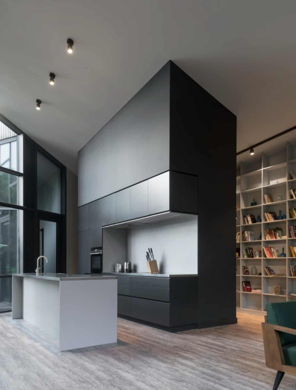 The kitchen features a tall vaulted ceiling, custom black cabinets, and a center island with bar seating.