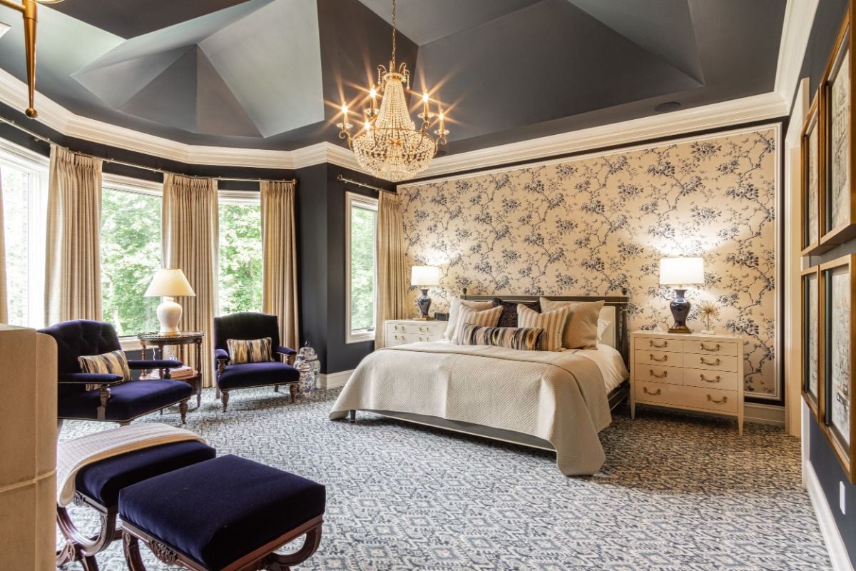 The en-suite features a wall-to-wall carpet, a queen-size bed, and a chandelier that gives the room a luxurious feel.