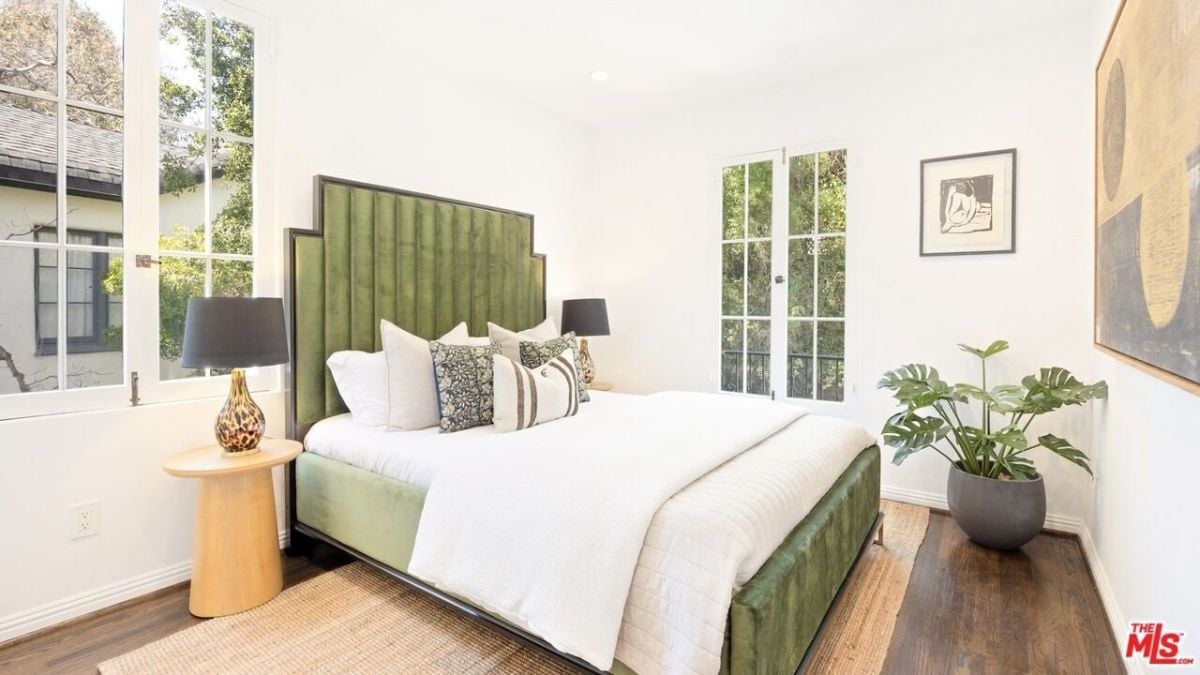 The bedroom features a double-sized bed, hardwood flooring, and an area rug.