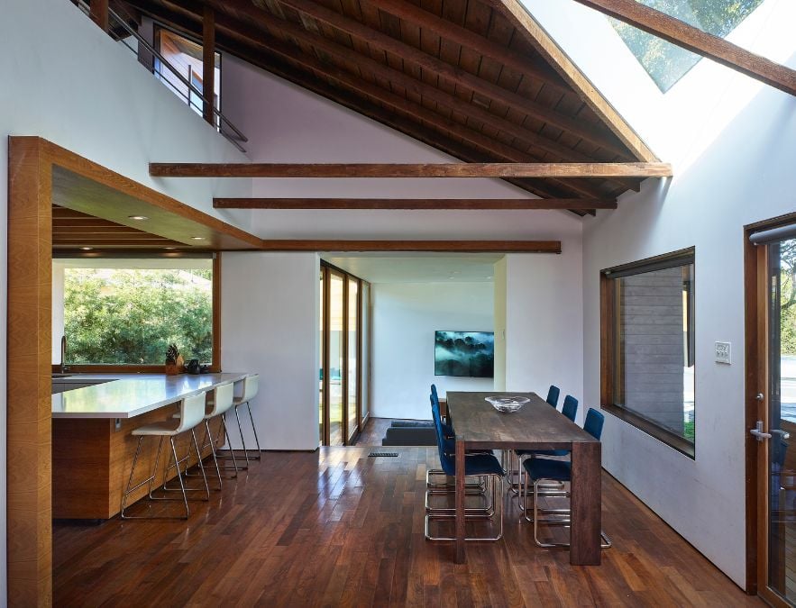 This image captures the dining area with a wooden table and chairs, with a glimpse of the kitchen area.
