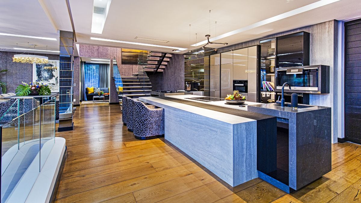 You can see the wooden flooring throughout the house, and the kitchen has a gray-colored decor and furnishings.