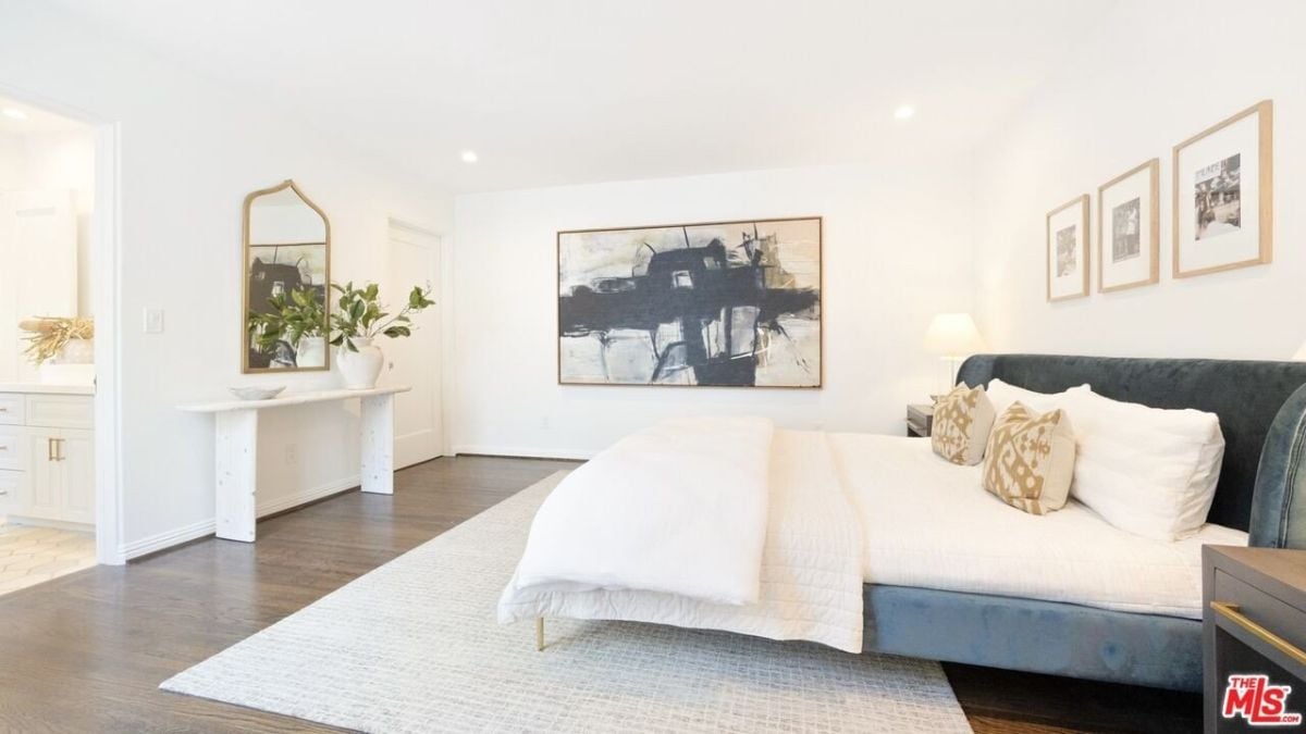 The bedroom features a queen-sized bed surrounded by artwork.
