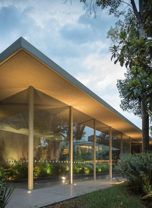 This captivating photograph viewed from the exterior, captures the covered swimming pool area enclosed by an expansive glass wall.