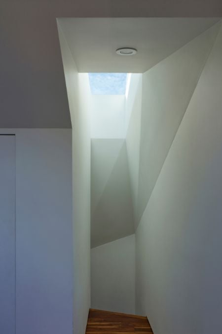A photo from the top of the staircase that is flooded in natural light from the skylight above.