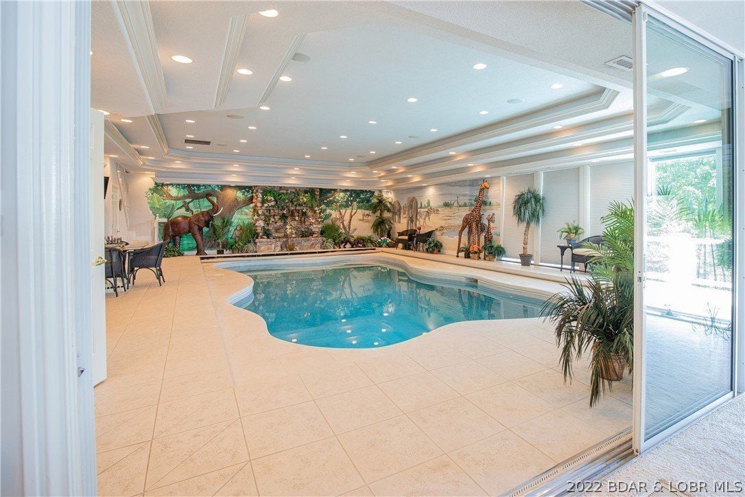 The indoor pool features tile flooring and the room is decorated with animal statues.