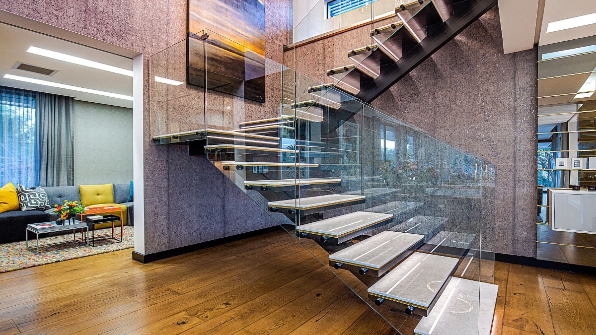 The floating timber staircase that climbs to the upper level is enclosed by a double-volume art gallery room.