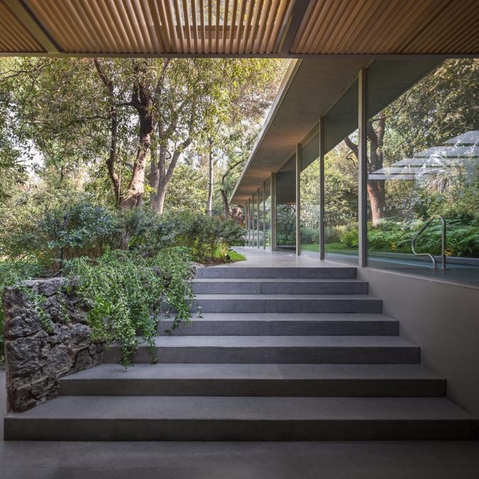 This image highlights a set of stairs leading up to the rear entrance of a residence, surrounded by lush vegetation that adds a touch of natural beauty to the outdoor space.