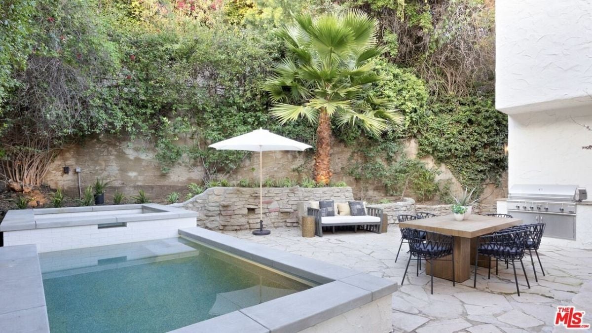 The patio features an outdoor sofa and hardwood table that blends well with the stone flooring.