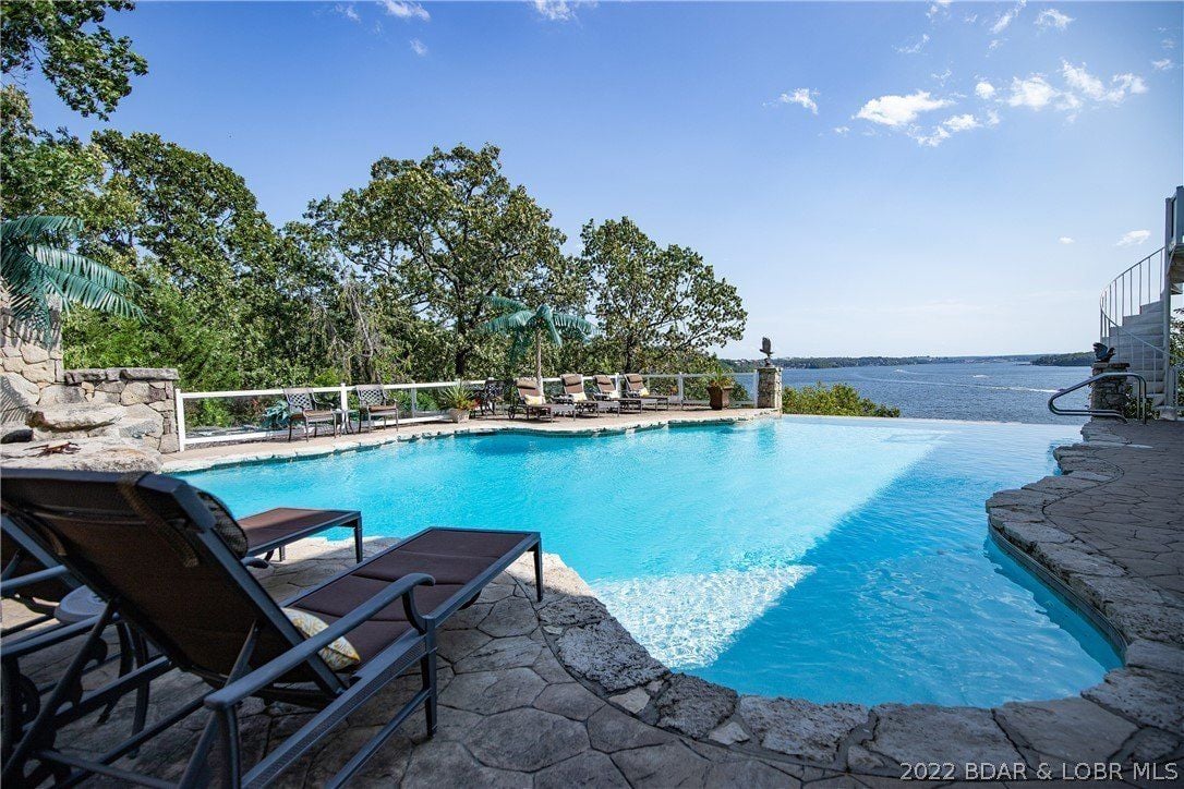 The swimming pool features a concrete deck and sunloungers facing the lake.